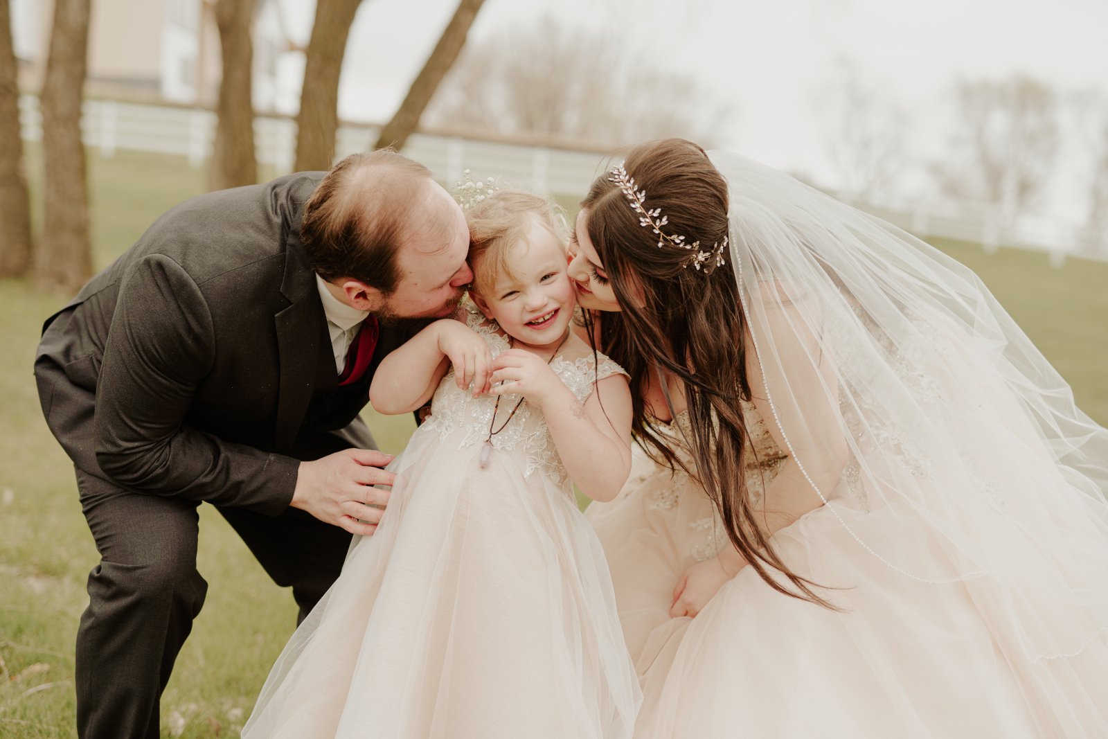 Wedding couple kissing daughter on the cheek Wedding couple kissing daughter on the cheek