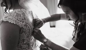 Mother of the bride buttoning brides dress