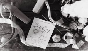 Wedding detail photo of invitation and rings with wood background
