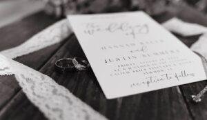 Wedding detail photo of invitation and rings with wood background