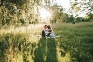 Engaged couple sitting in a grass field