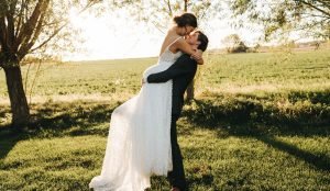 Bride getting picked up by groom about to kiss