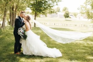 Wedding couple kissing with veil in the wind