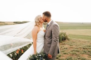 Wedding couple kissing with veil in the wind