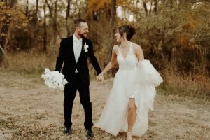 Wedding couple holding hands running in the forest