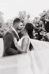 Wedding couple kissing with veil in front of camera