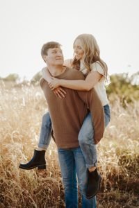 Engaged couple piggy back ride in wheatgrass