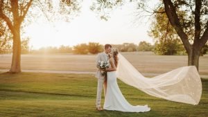 Wedding couple kissing with veil in the air
