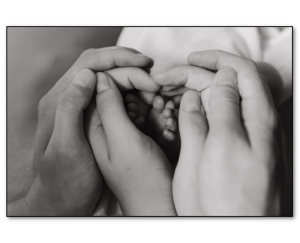 Newborn feet surrounded by families hands to make a heart