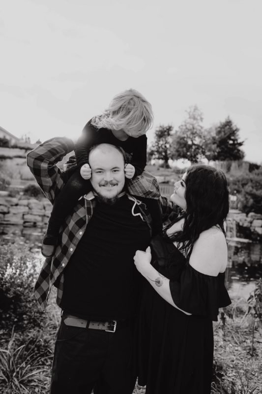 Child Sitting On Dad's Shoulder With Mom