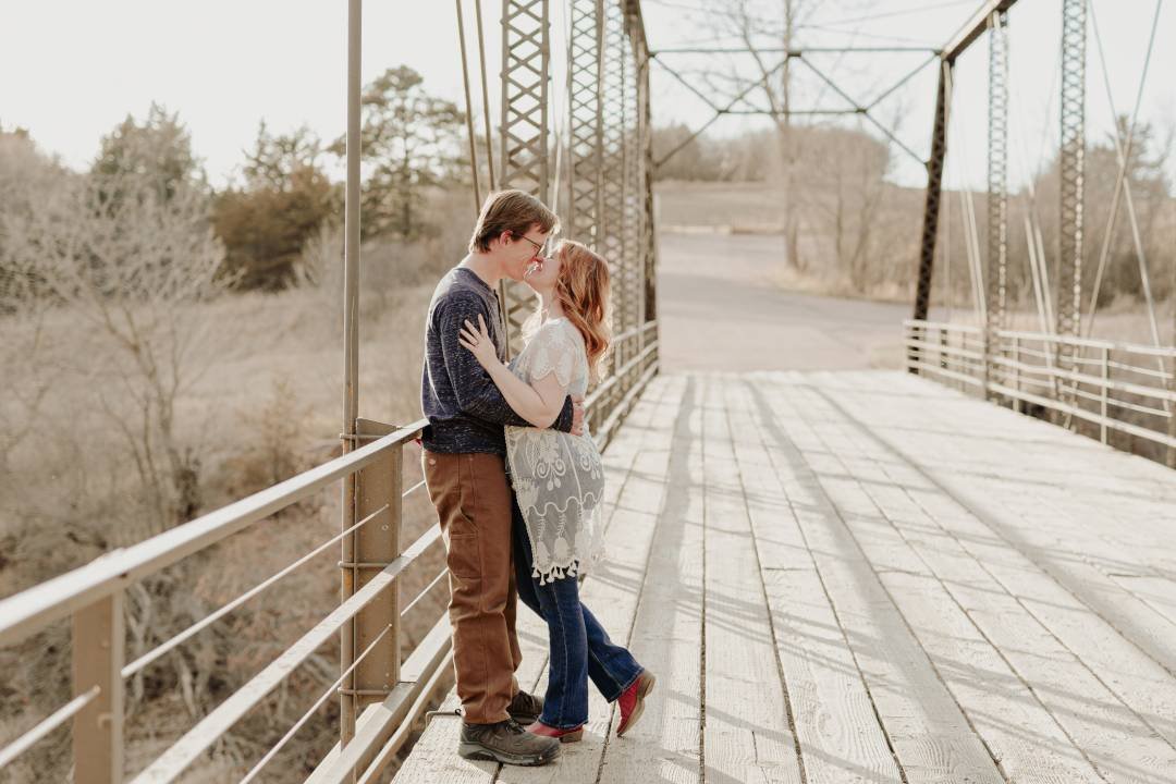 Engaged couple on bridge about to kiss